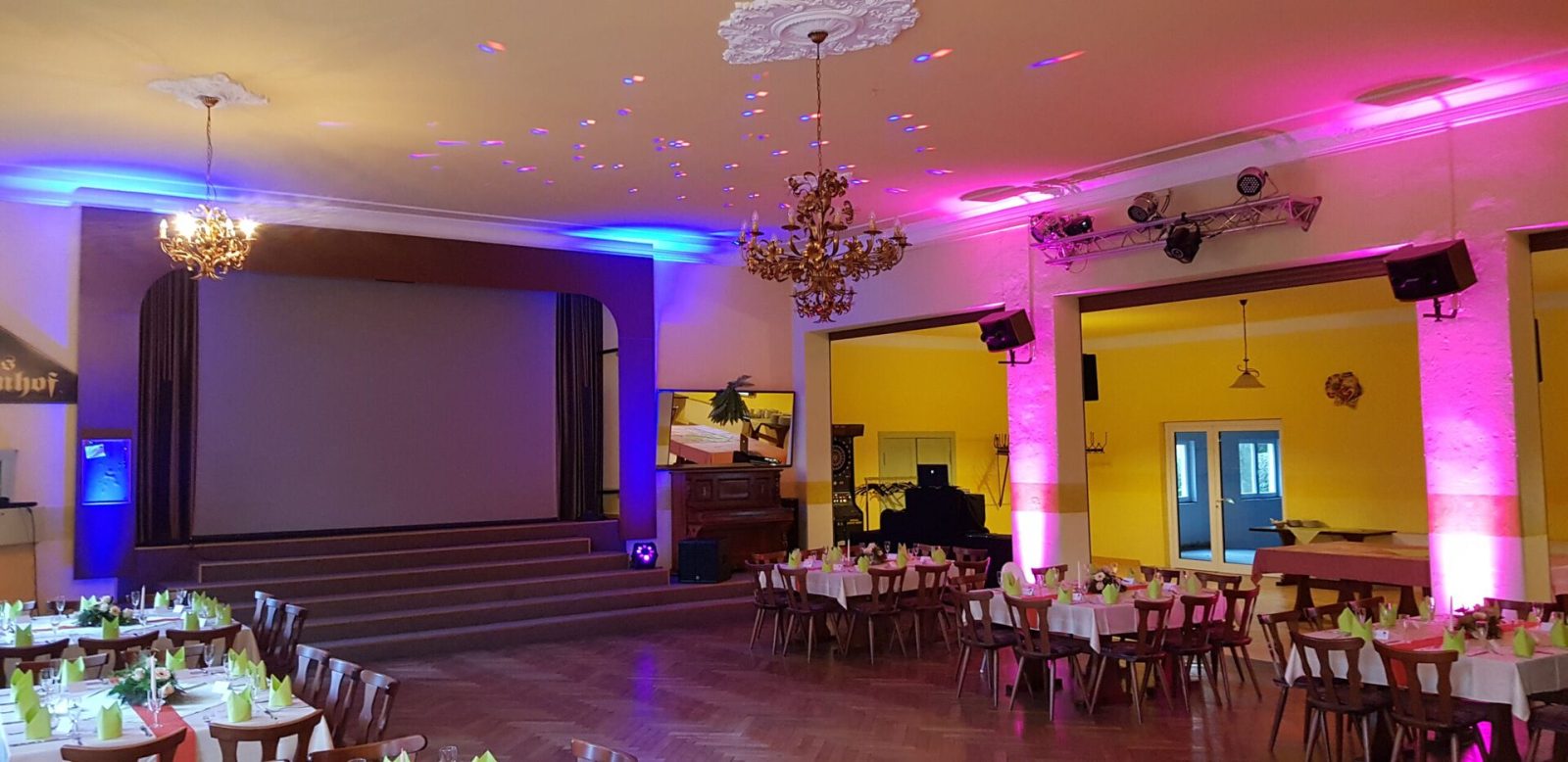 Saal mit farbigem Uplighting und Bühne